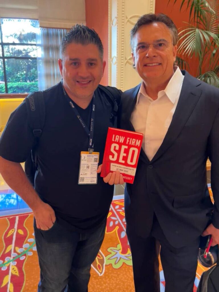 Keith Givens and a Hennessey Digital team member holding a copy of Law Firm SEO at Mass Torts Made Perfect