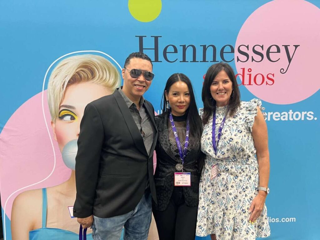 Three Hennessey Studios team members at the company backdrop at the B2B Marketing Expo