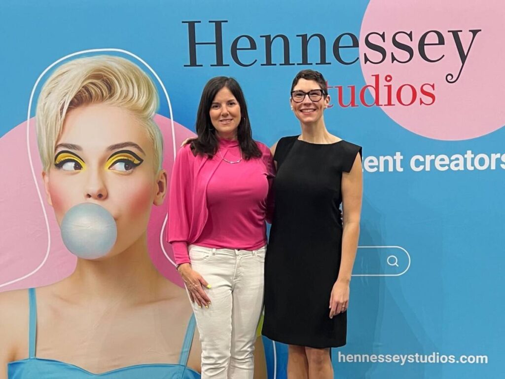 Two Hennessey Studios team members at the company backdrop at the B2B Marketing Expo