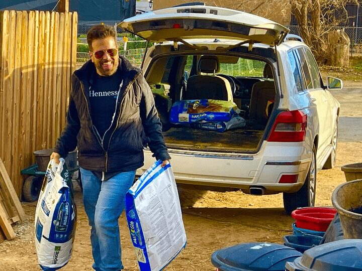 Team member unloading bags of pet food from an SUV for a donation